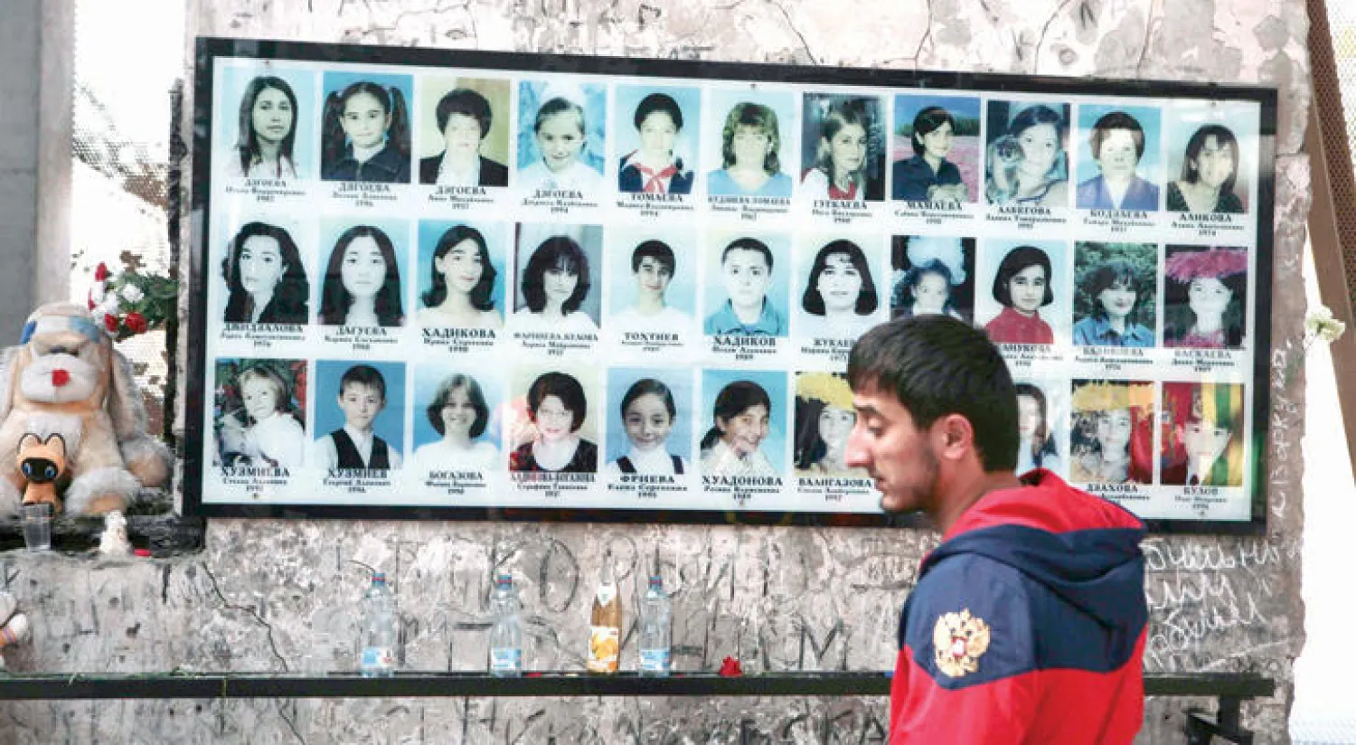 رجل يقف بجانب صور لضحايا حادث احتجاز الرهائن في بيسلان أمس (رويترز)