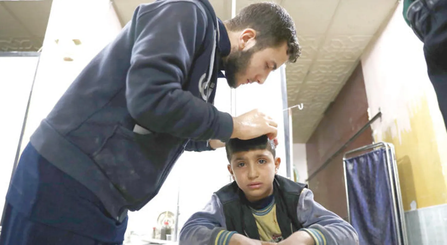 طفل سوري يبكي أثناء تضميد جراح في رأسه في مدينة دوما أمس (أ.ف.ب)
