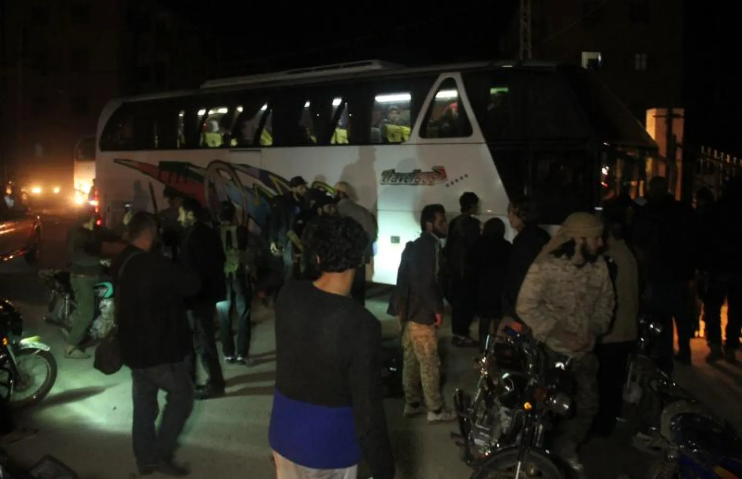 حافلات تنقل السوريين الذين تم إجلاؤهم من مدينتين سوريتين محاصرتين في إدلب (أ.ف.ب)