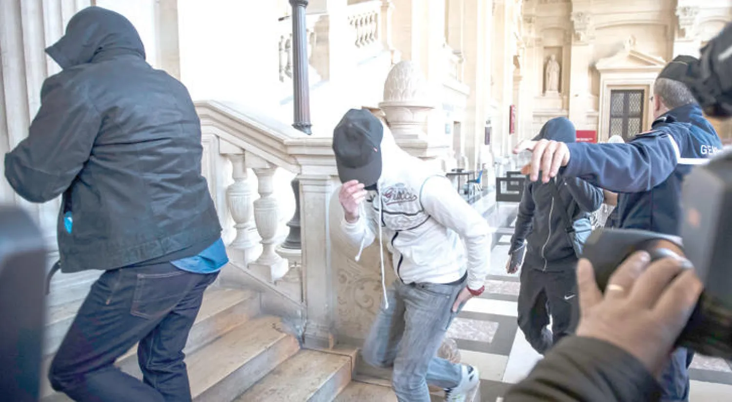 عناصر شبكة «كان - تورسي» يغطون وجوههم لدى وصولهم إلى قصر العدالة في باريس لحضور أولى جلسات الاستماع في العاصمة باريس امس (إ.ب.أ)