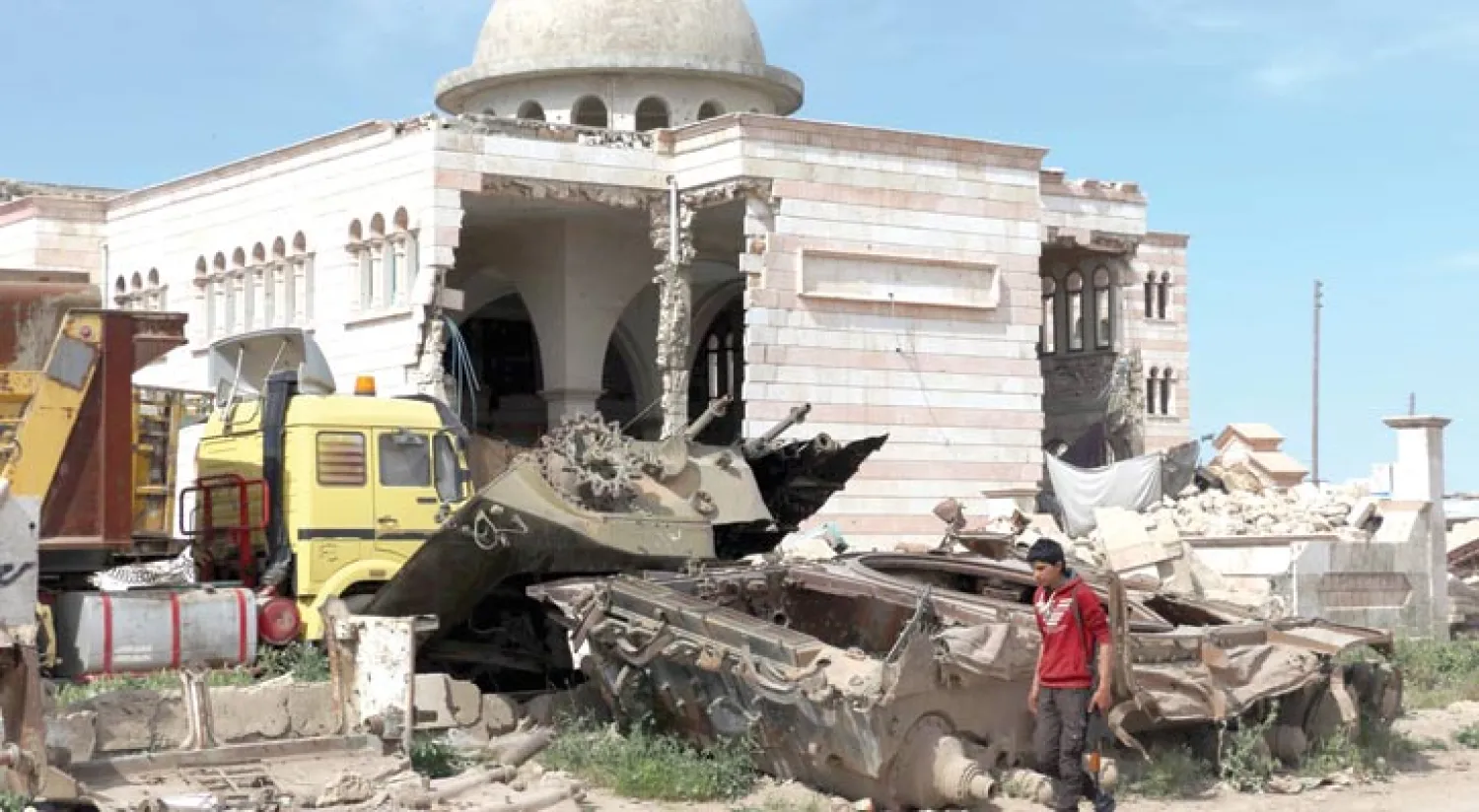 شاب مسلح يمر أمام «مسجد الفاروق» المدمر بفعل القصف في مدينة أعزاز بشمال سوريا أمس (أ.ف.ب)