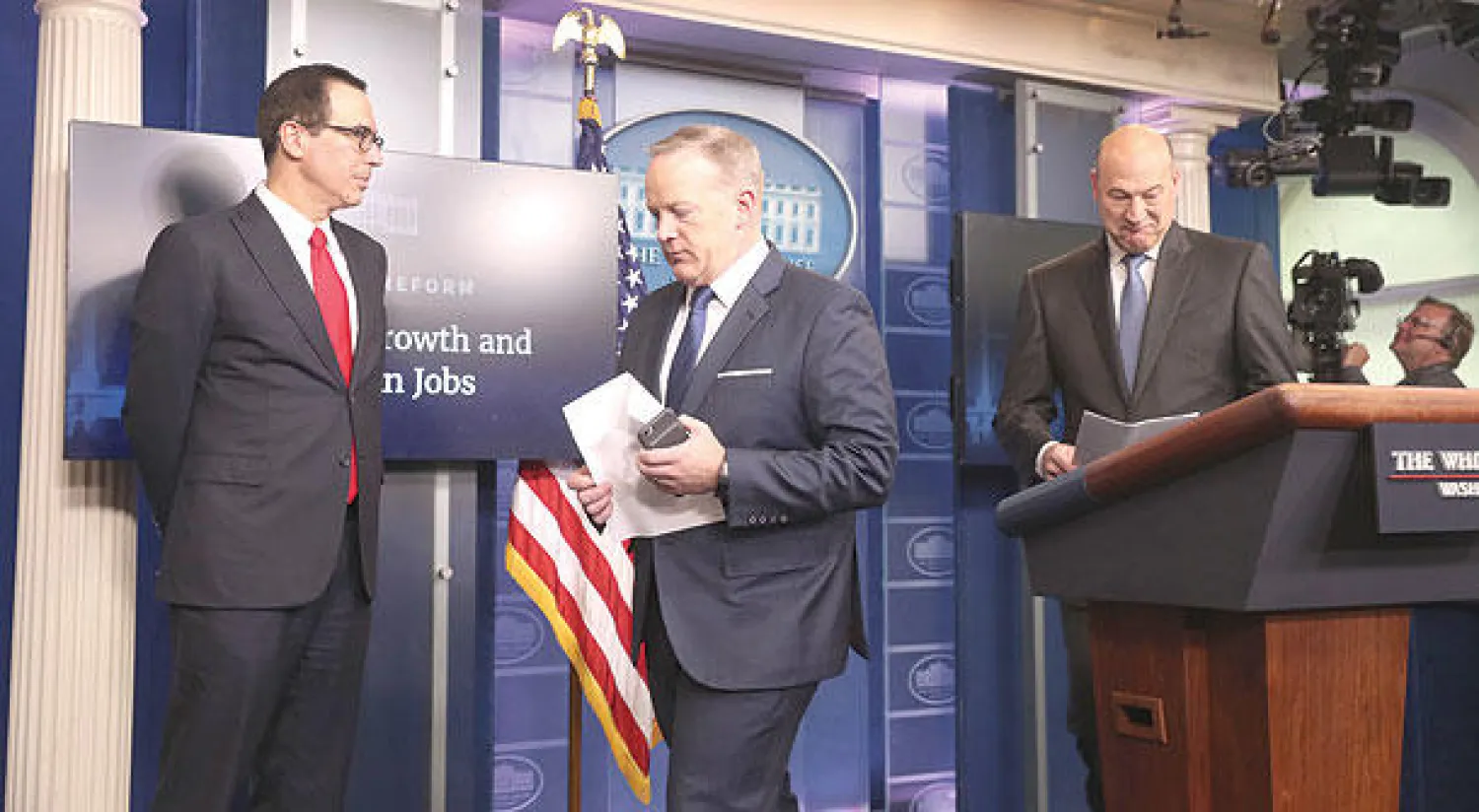 الناطق باسم البيت الأبيض شون سبايسر بين المستشار الاقتصادي غاري كوهين ومنوتشين في واشنطن أمس (أ.ب)