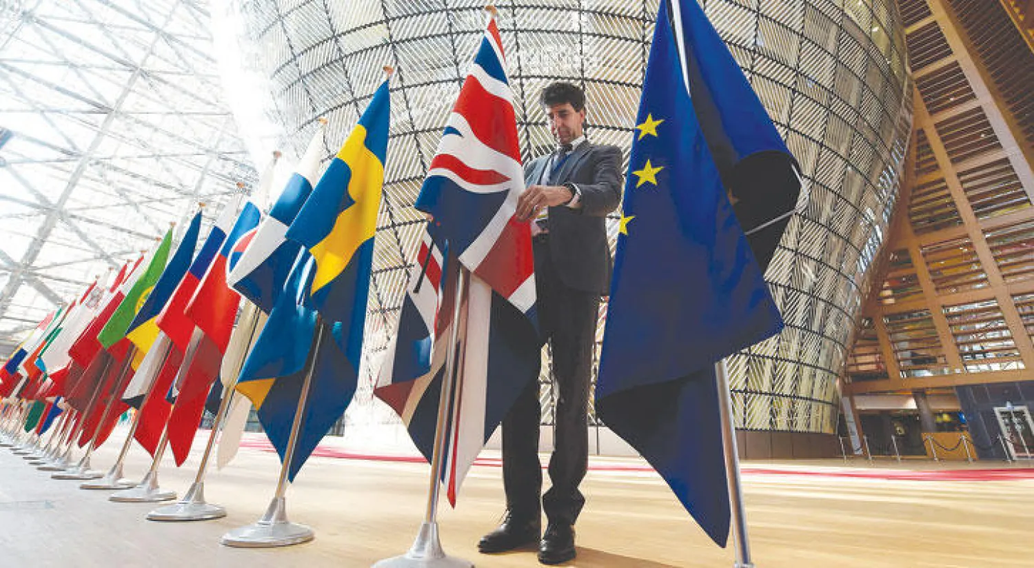 موظف في المجلس الأوروبي ببلجيكا يعدل علم بريطانيا قبيل قمة القادة الأوروبيين (أ.ف.ب)