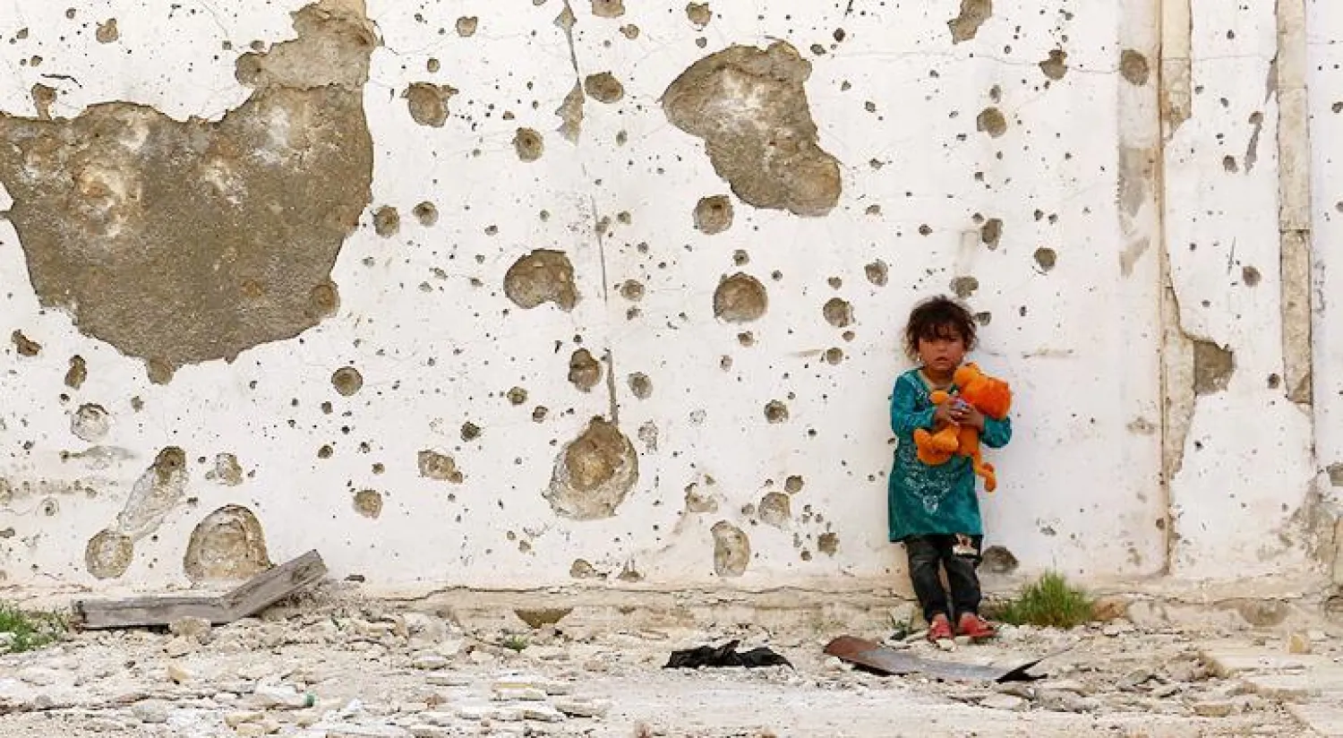 طفلة سورية تلعب أمام جدار متضرر في مدينة أعزاز على الحدود مع تركيا (أ.ف.ب)
