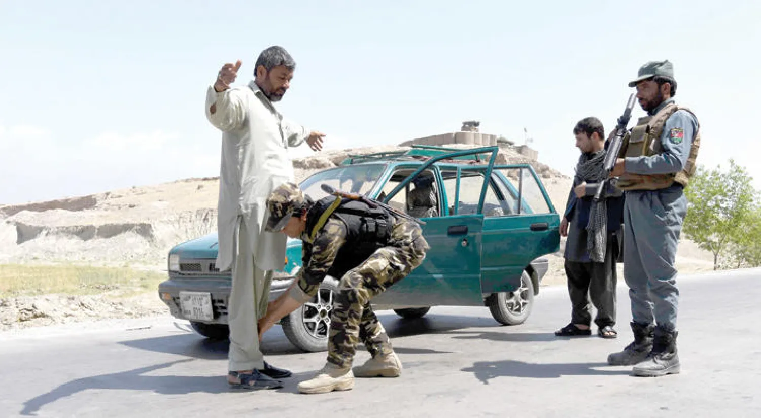 عناصر من قوات الأمن في ولاية ننجرهار تفتش أفغانياً في الطريق السريع إلى جلال آباد مع ازدياد وتيرة عمليات طالبان (إ.ب.أ)