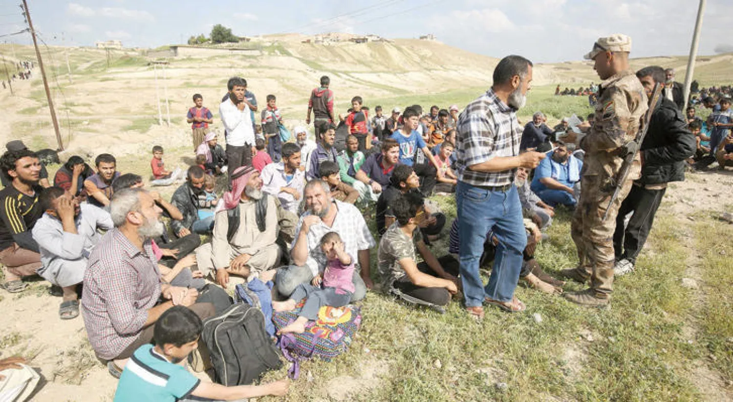 جندي عراقي يتفحص أوراق نازحين فروا أمس من حي المشيرفة شمال غربي الموصل مع بدء القتال فيه (أ.ف.ب)