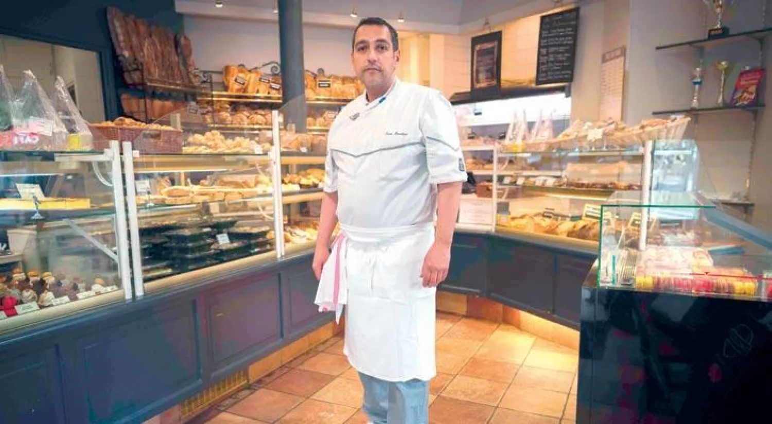 سمير بنعطور الذي منح الجائزة أمام محله في باريس (أ.ف.ب)