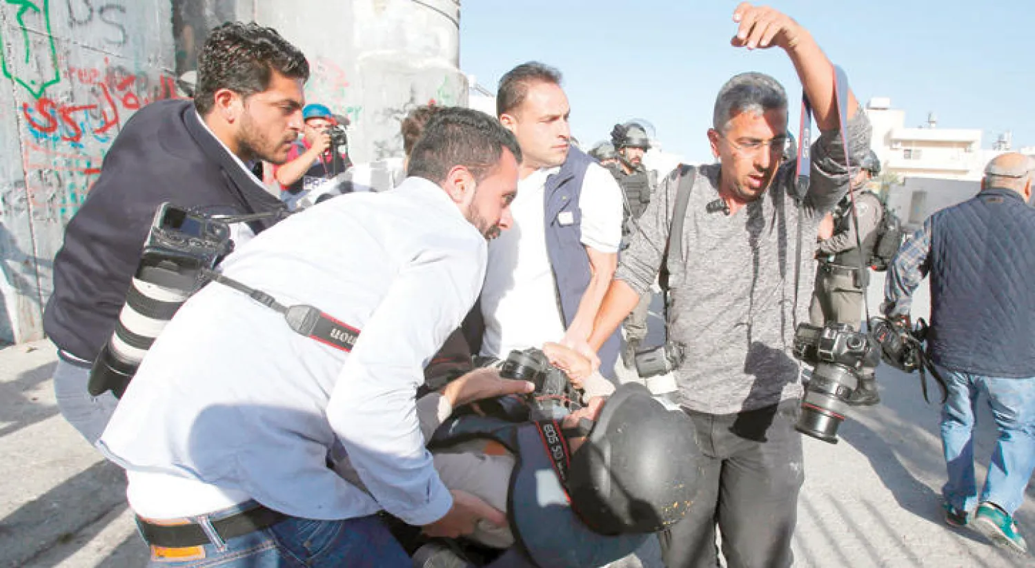 صحافيون ينقلون زميلاً لهم أصيب خلال اعتداء القوات الإسرائيلية على مظاهرة داعمة للأسرى في بيت لحم أمس (أ.ف.ب)