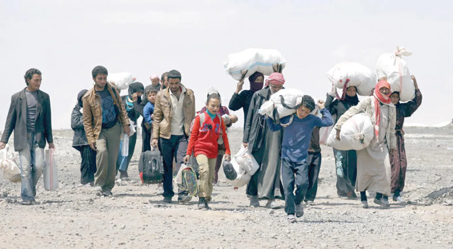 نازحون من مدينة الرقة السورية يحملون ممتلكاتهم لدى مغادرتهم مخيماً في بلدة عين عيسى (رويترز)