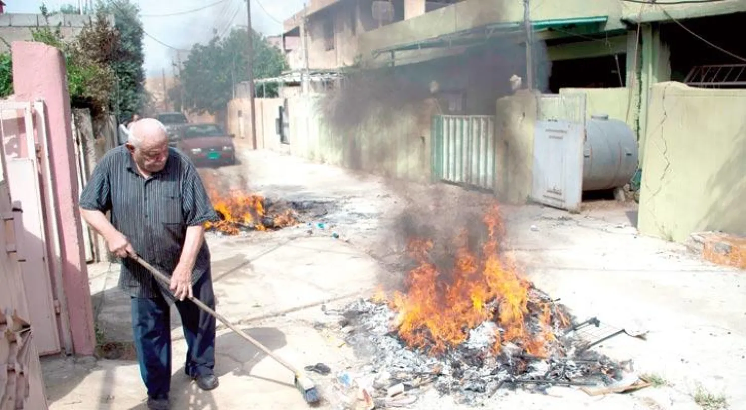أحد سكان قرقوش يحرق مخلفات «داعش» في أحد أزقة البلدة (أ.ف.ب)