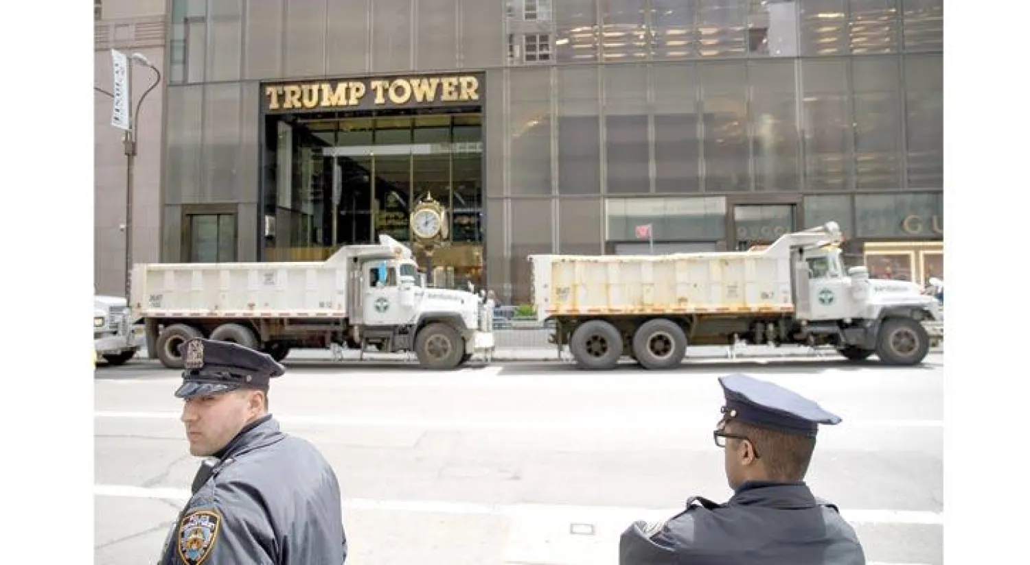 رجال شرطة نيويورك يراقبون برج ترمب وتبدو شاحنات تؤمن المدخل الرئيسي (أ.ف.ب)