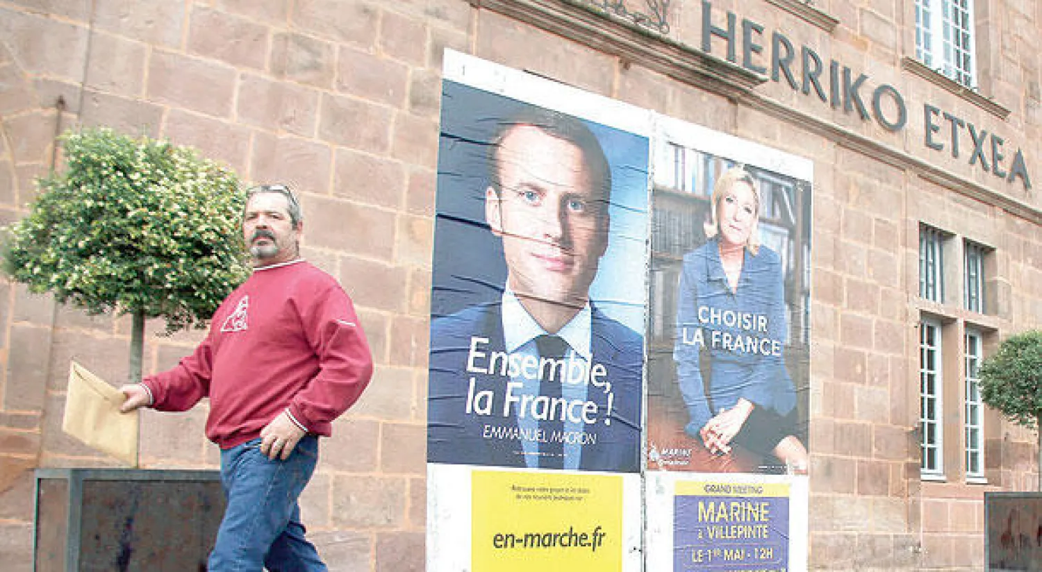 فرنسي يمر أمام ملصقين لمرشحي الرئاسة المتنافسين ماكرون ولوبان (أ.ب)