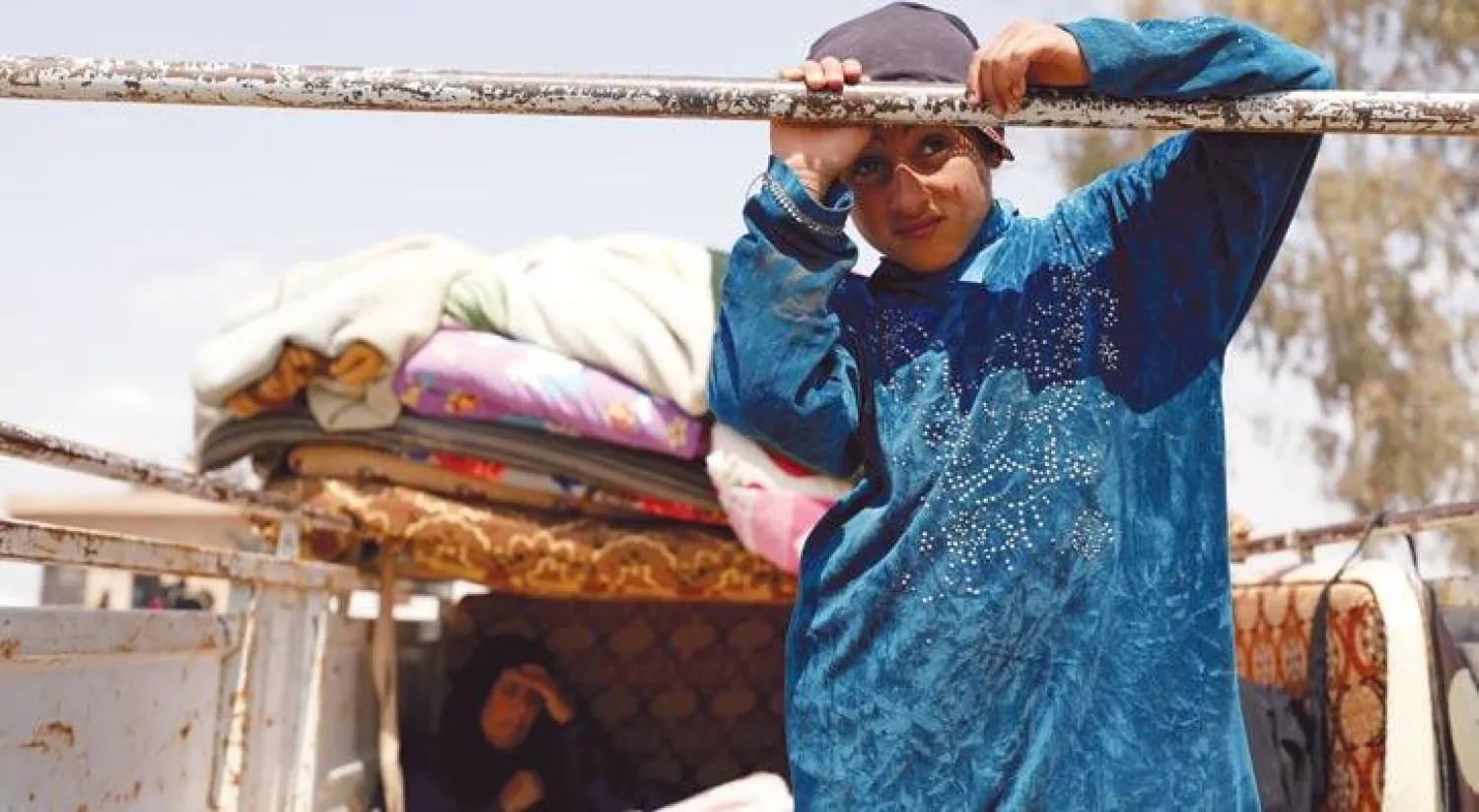 طفلة نازحة من مدينة الرقة هربا من المعارك فوق عربة نقل مع متعلقات عائلتها في مخيم عين عيسى (رويترز)