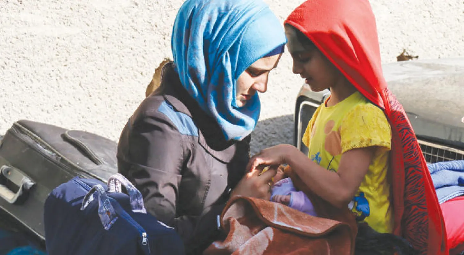 أم وابنتها في نقطة تجمع في برزة تمهيدا لإجلاء معارضي النظام من الضاحية الدمشقية أمس (أ.ف.ب)