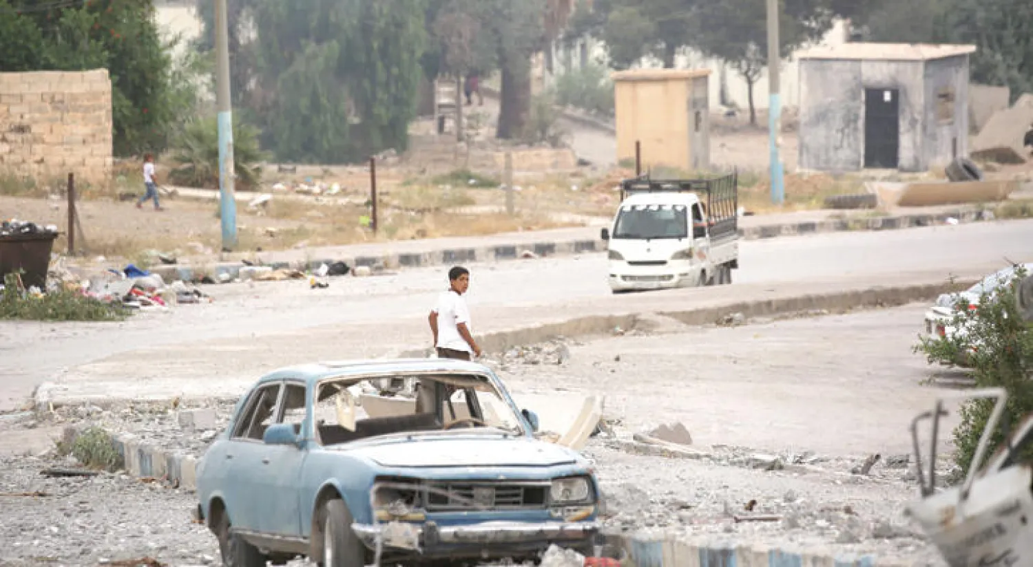 فتى سوري يمر قرب سيارة مدمرة في مدينة الطبقة التي سيطرت عليها أخيراً الميليشيات الكردية المدعومة من واشنطن (أ.ف.ب)