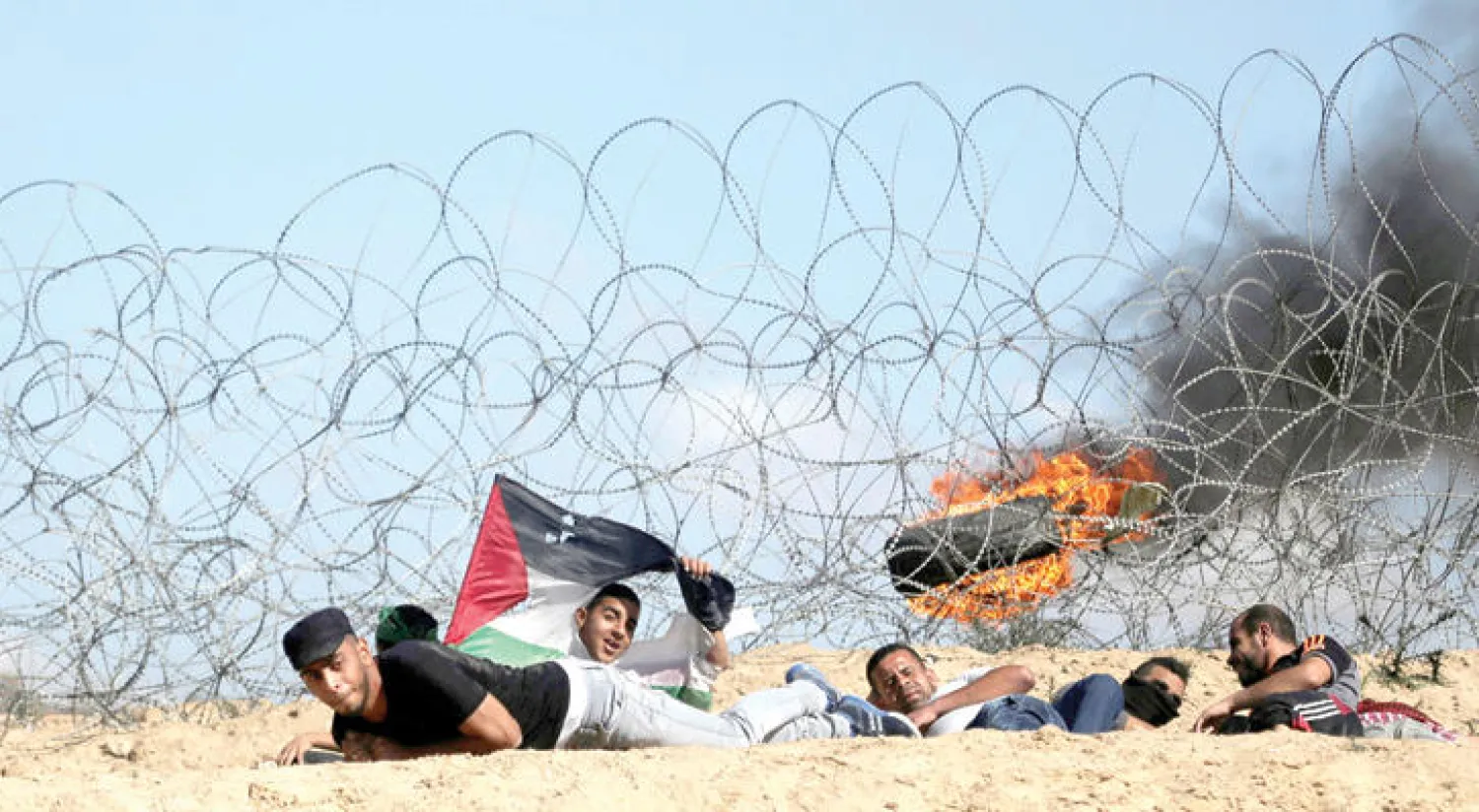 متظاهرون خلال اشتباكات مع جنود إسرائيليين قرب حدود غزة أمس (رويترز)