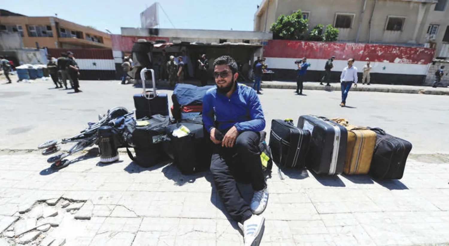 شاب من حي الوعر يتكئ على حقائب سفر لمقاتلين ومدنيين قبل تهجيرهم إلى ادلب أمس (رويترز)
