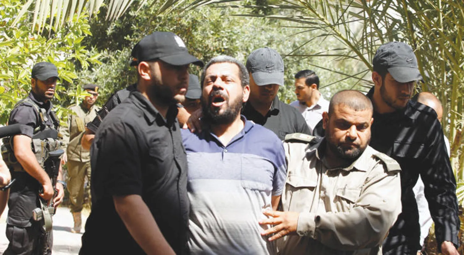 عناصر من أمن «حماس» يقودون أحد المتهمين بقتل مازن فقها إلى قاعة المحكمة أمس (رويترز)