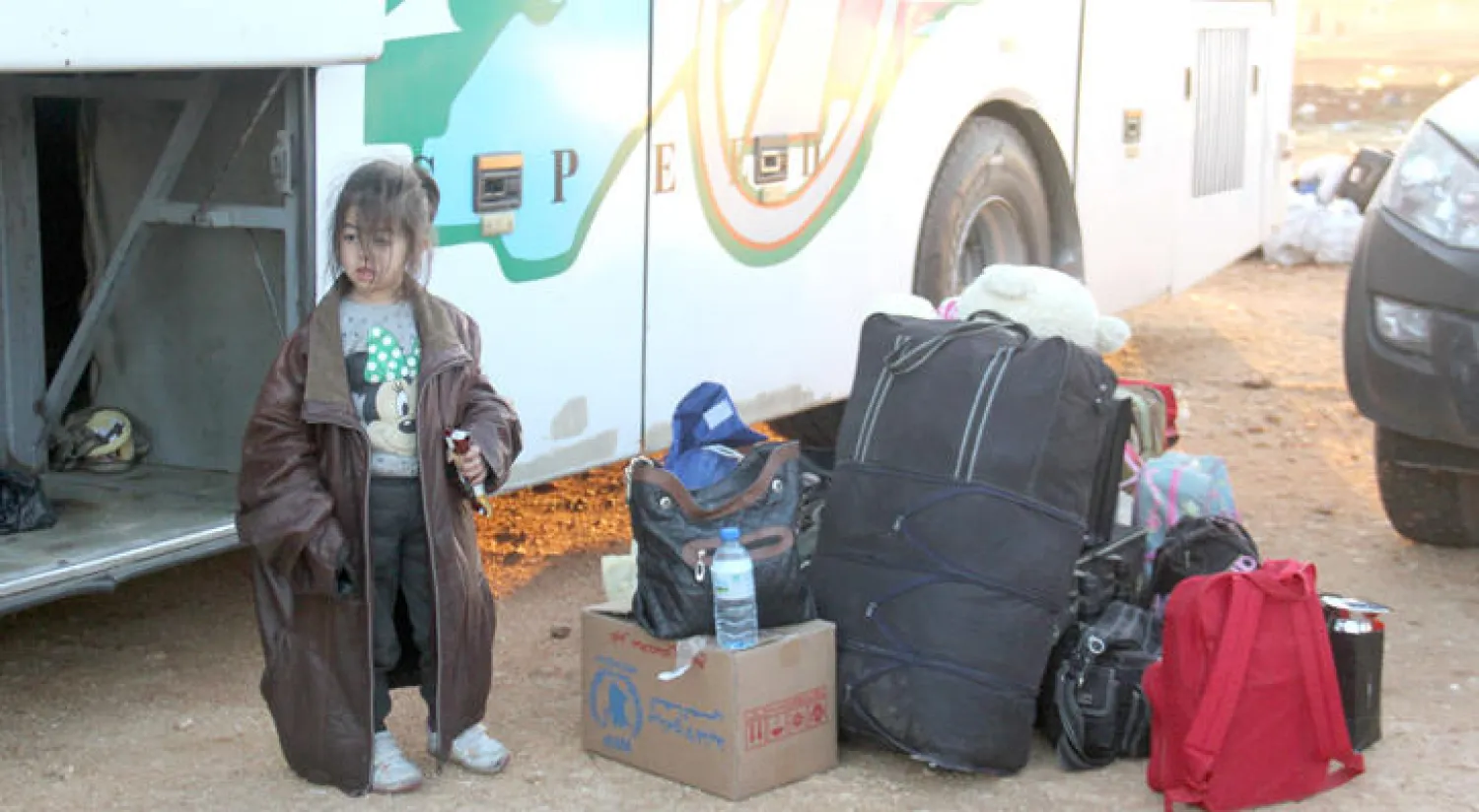 طفلة سورية من مهجري حي الوعر تقف قرب حوائج العائلة بعد وصولها أمس إلى قرية معرة الإخوان شمال إدلب (أ.ف.ب)