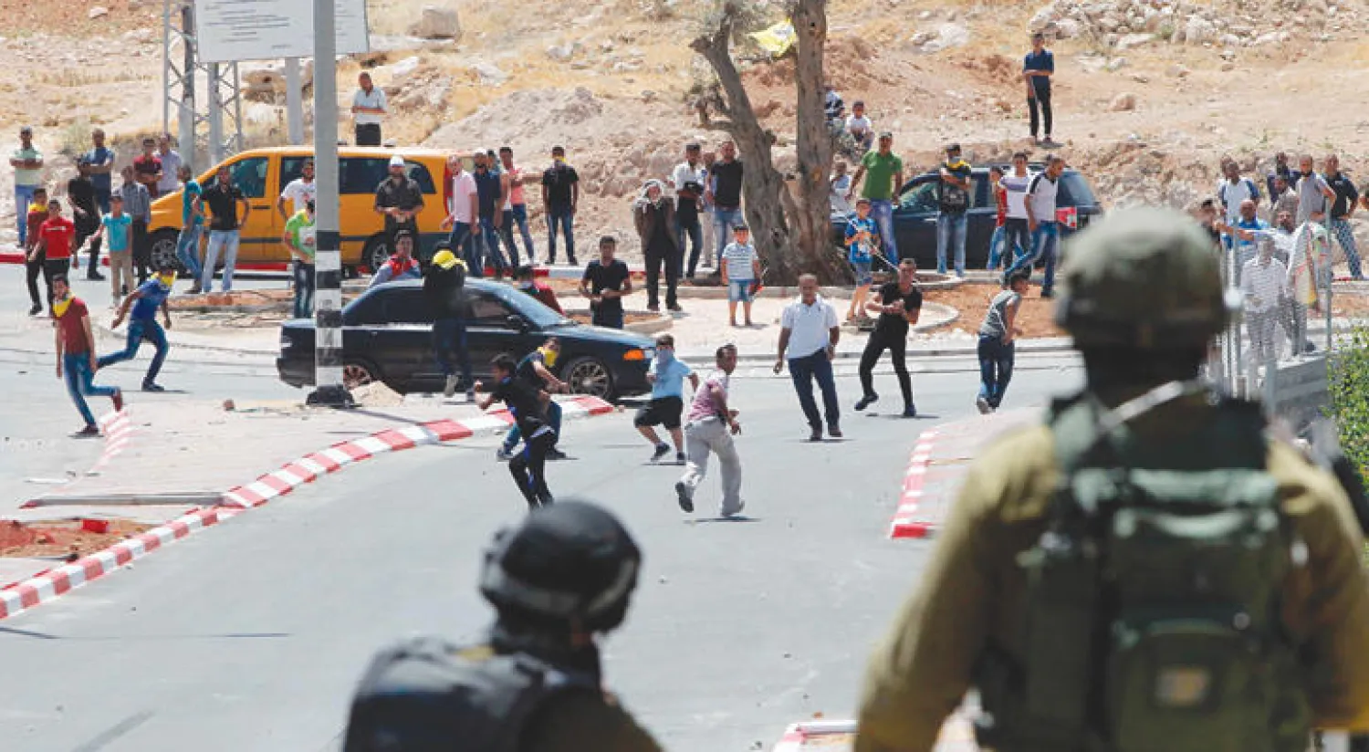 فلسطينيون يرشقون قوات أمن إسرائيلية بالحجارة عند مدخل بلدة يطا قرب الخليل (أ.ف.ب)