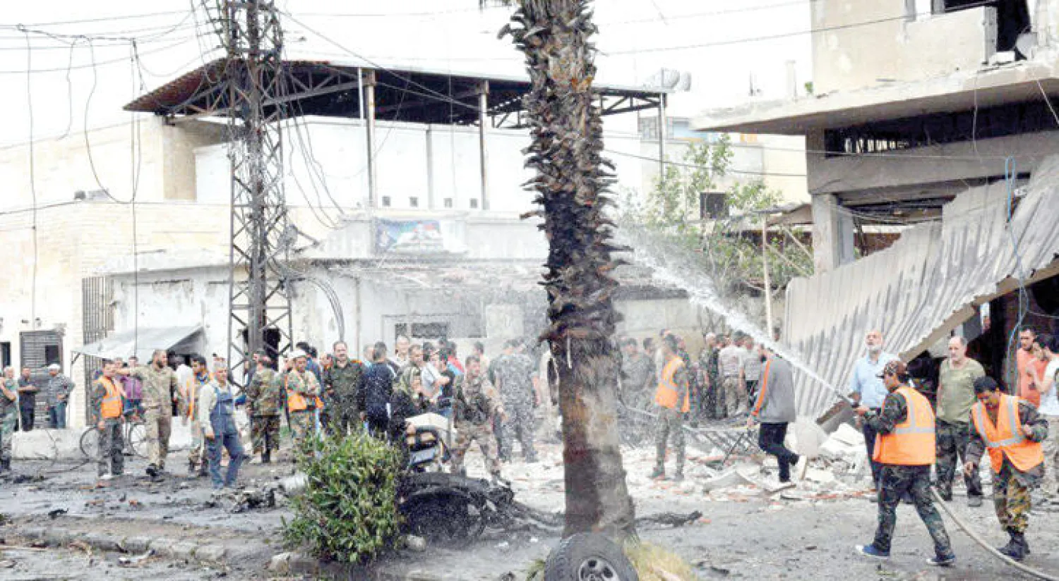 رجال إطفاء يحاولون التغلب على نيران تفجير سيارة في حي الزهراء بحمص أمس (رويترز)