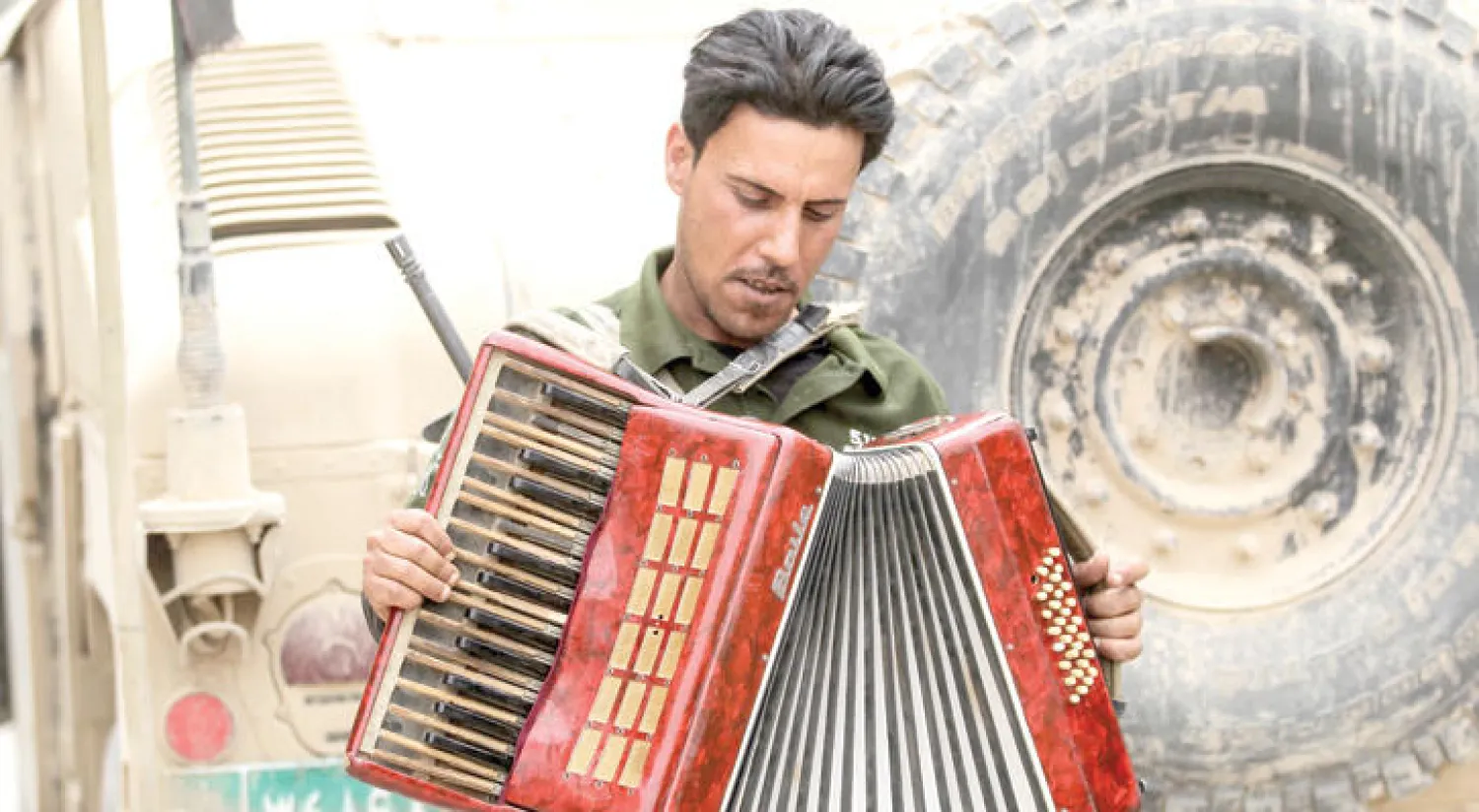 جندي عراقي يعزف الأكرديون خلال استراحة من المعارك في غرب الموصل أمس (أ.ف.ب)