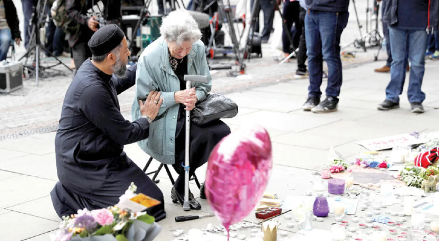 داعية مسلم يهدئ من روع امرأة يهودية في ميدان «سانت ألبرت» أمس بعد أن وضعت إكليلاً من الورود على أرواح ضحايا تفجير مانشستر الانتحاري (رويترز)