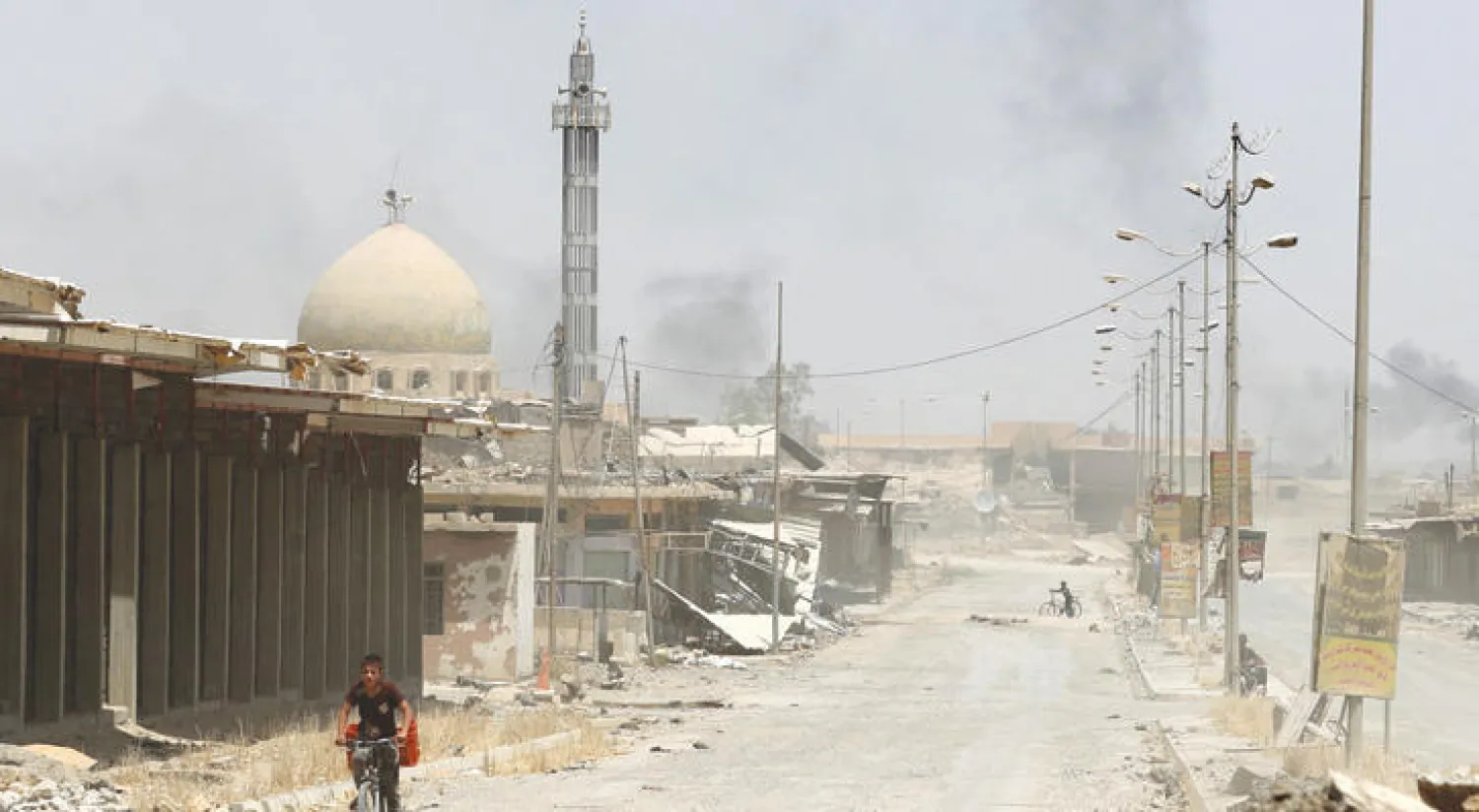 فتى يستقل دراجة هوائية في حي الصحة بالجانب الغربي من الموصل أمس (أ.ف.ب)