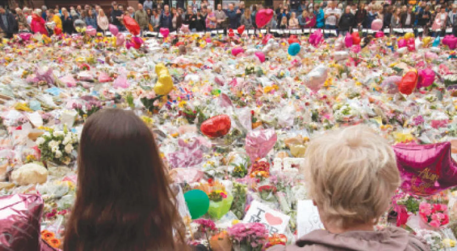 بريطانيون يتطلعون إلى آلاف من باقات الورود وضعت في ميدان «سانت آن» بوسط مانشستر ترحماً على أرواح ضحايا الهجوم الإرهابي (أ.ف.ب)