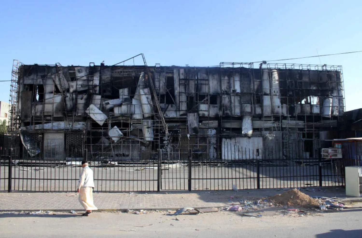 رجل يمر بمبنى متضرر عقب اشتباكات عنيفة بين فصائل متنافسة في منطقة أبو سليم في طرابلس (رويترز)