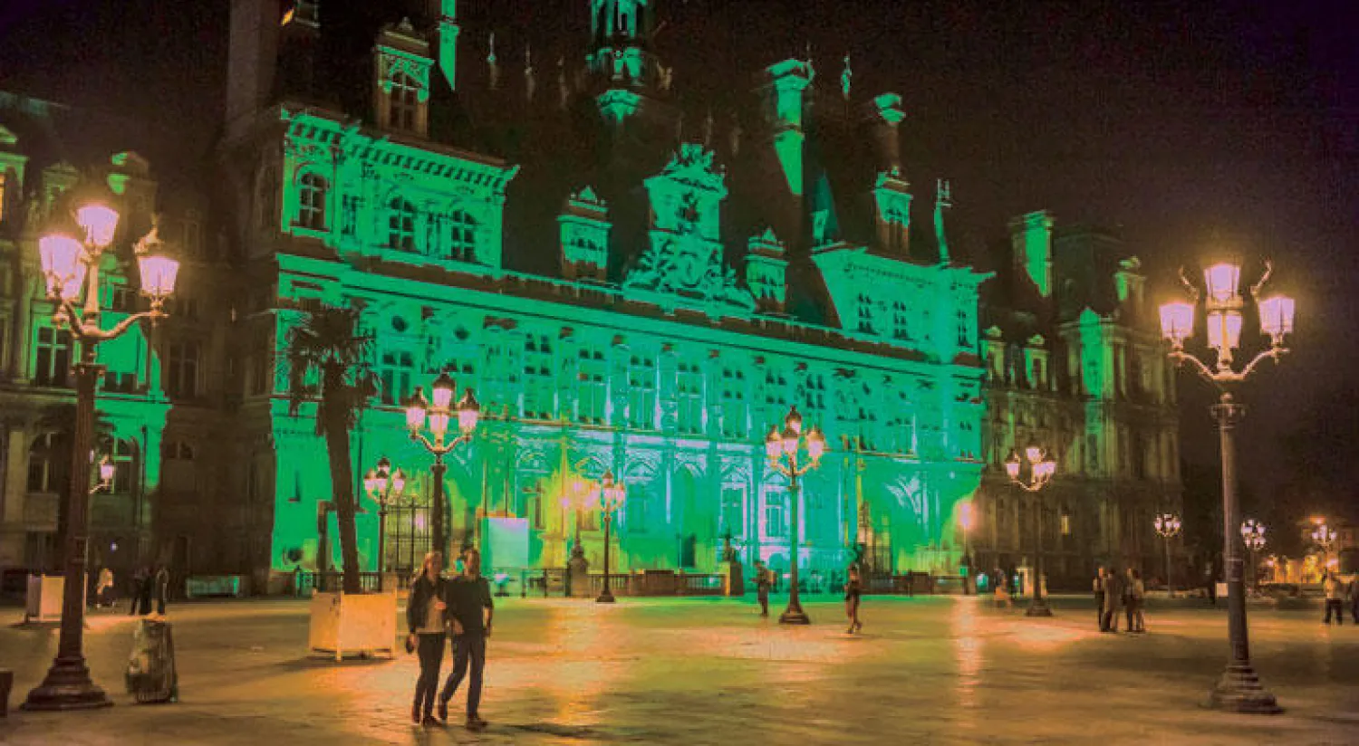 بلدية باريس تكتسي باللون الأخضر احتجاجاً على انسحاب واشنطن من اتفاقية باريس للمناخ (إ.ب.أ)