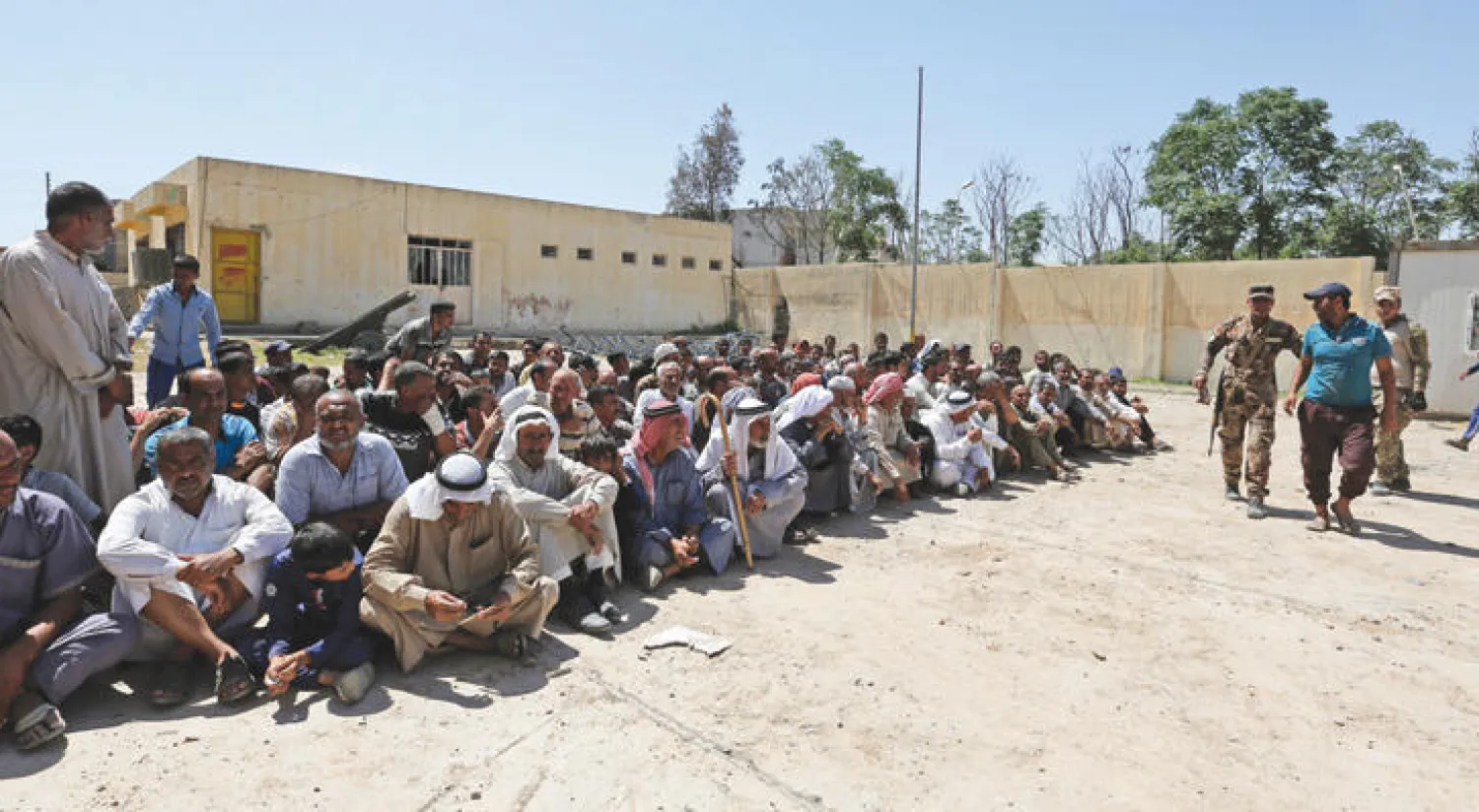 هاربون من معارك غرب الموصل ينتظرون تدقيق هوياتهم في مركز أمني غرب المدينة أمس (إ.ب.أ)