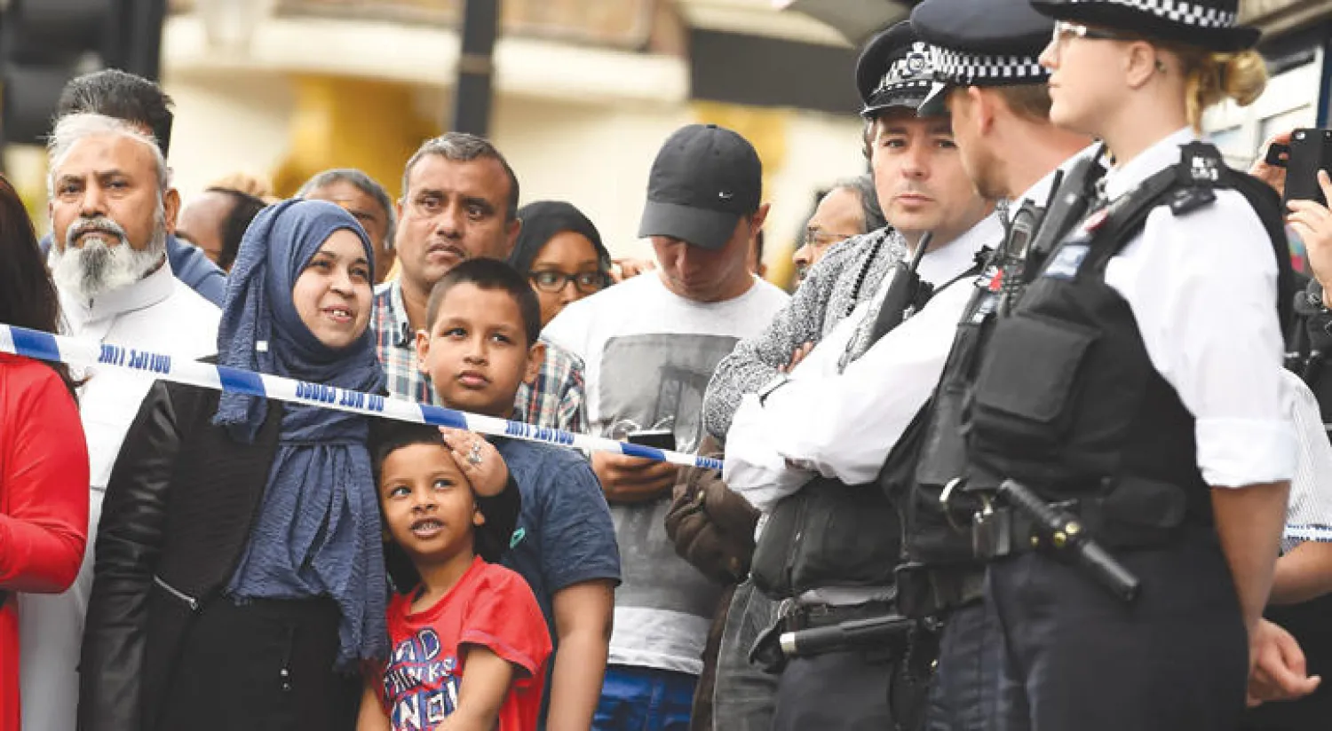 حشود وضباط شرطة في حي ايست هام بشرق لندن حيث جرت مداهمات واعتقالات أمس (أ. ف. ب)