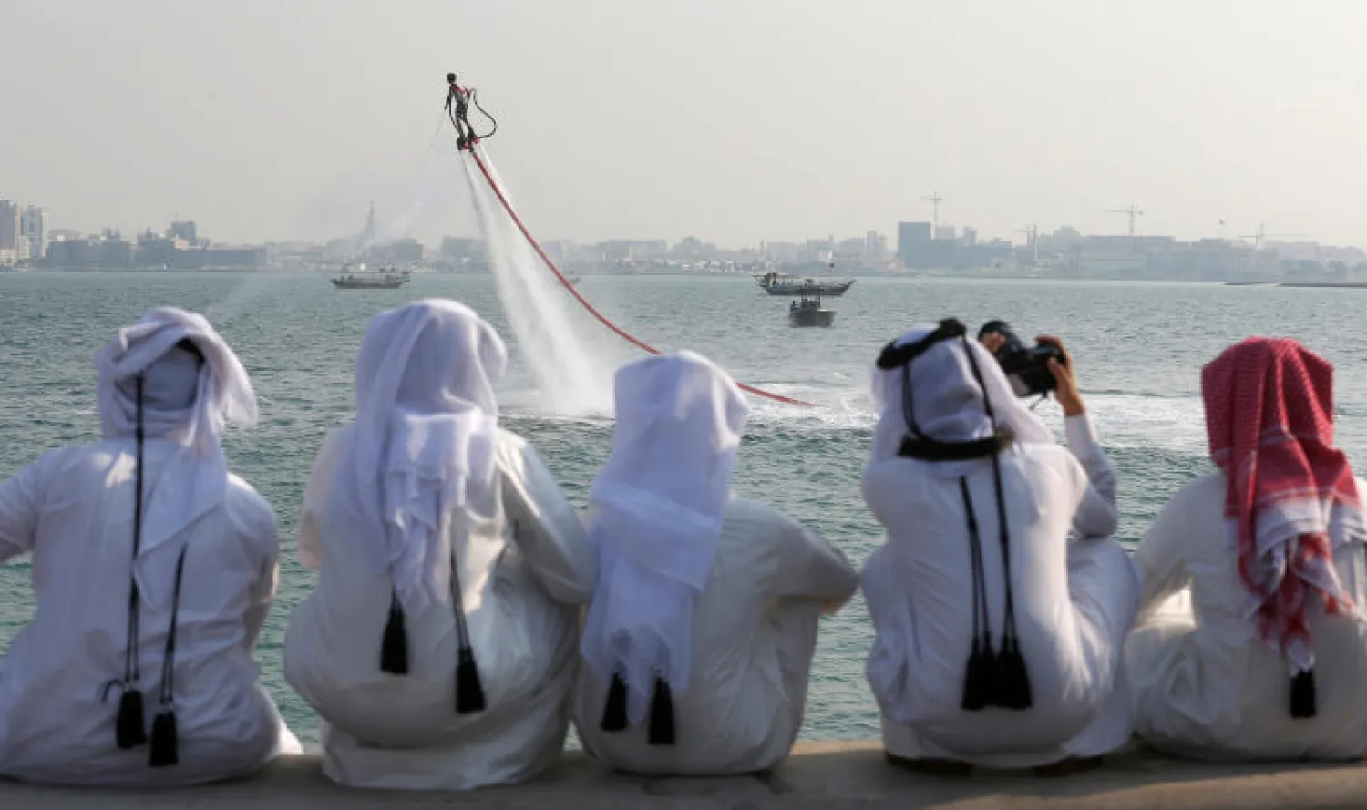 قطريون يشاهدون ألعابا مائية في الدوحة (رويترز)