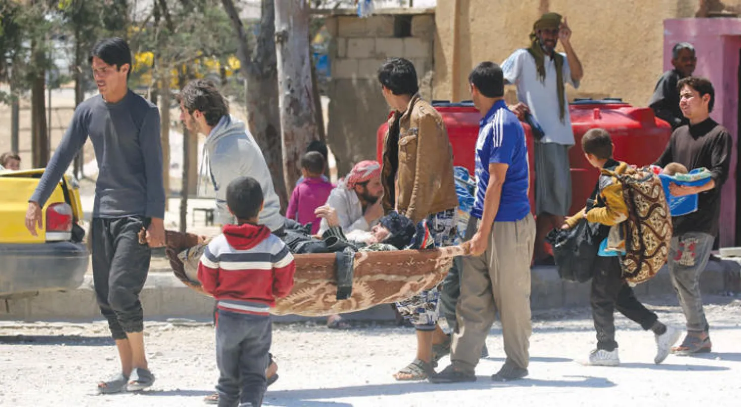 هاربون من تنظيم داعش في الرقة شمال سوريا يحملون امرأة مسنة في مخيم مؤقت أقيم للنازحين في بلدة عين عيسى (أ.ف.ب)