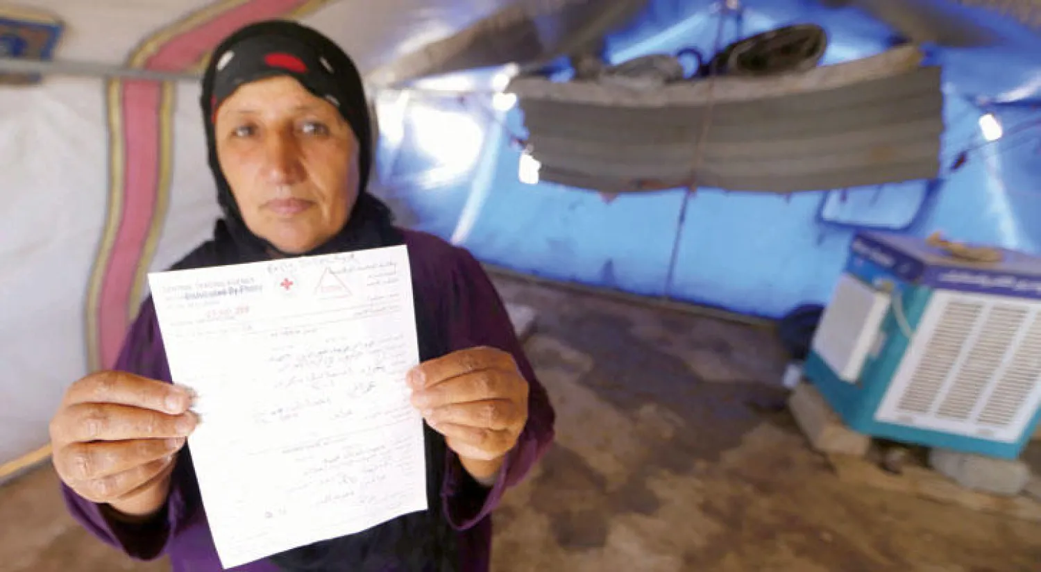 النازحة يسرى محمد تحمل رسالة من الصليب الأحمر تقول إن ولديها محتجزان لدى القوات الكردية (أ.ف.ب)