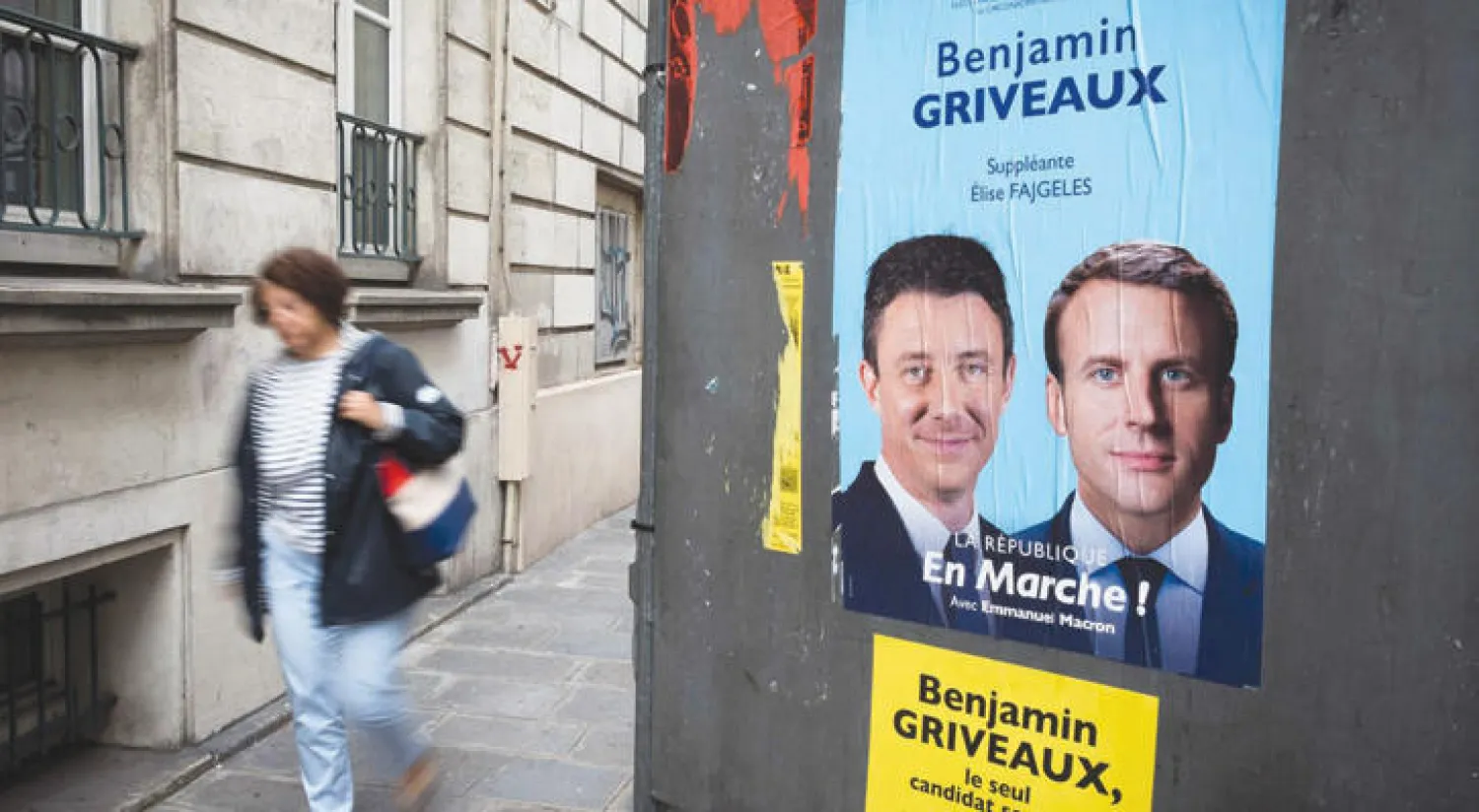 ملصق للحملة الانتخابية يظهر ماكرون مع مرشح آخر من حزبه {إلى الأمام} (أ.ف.ب)