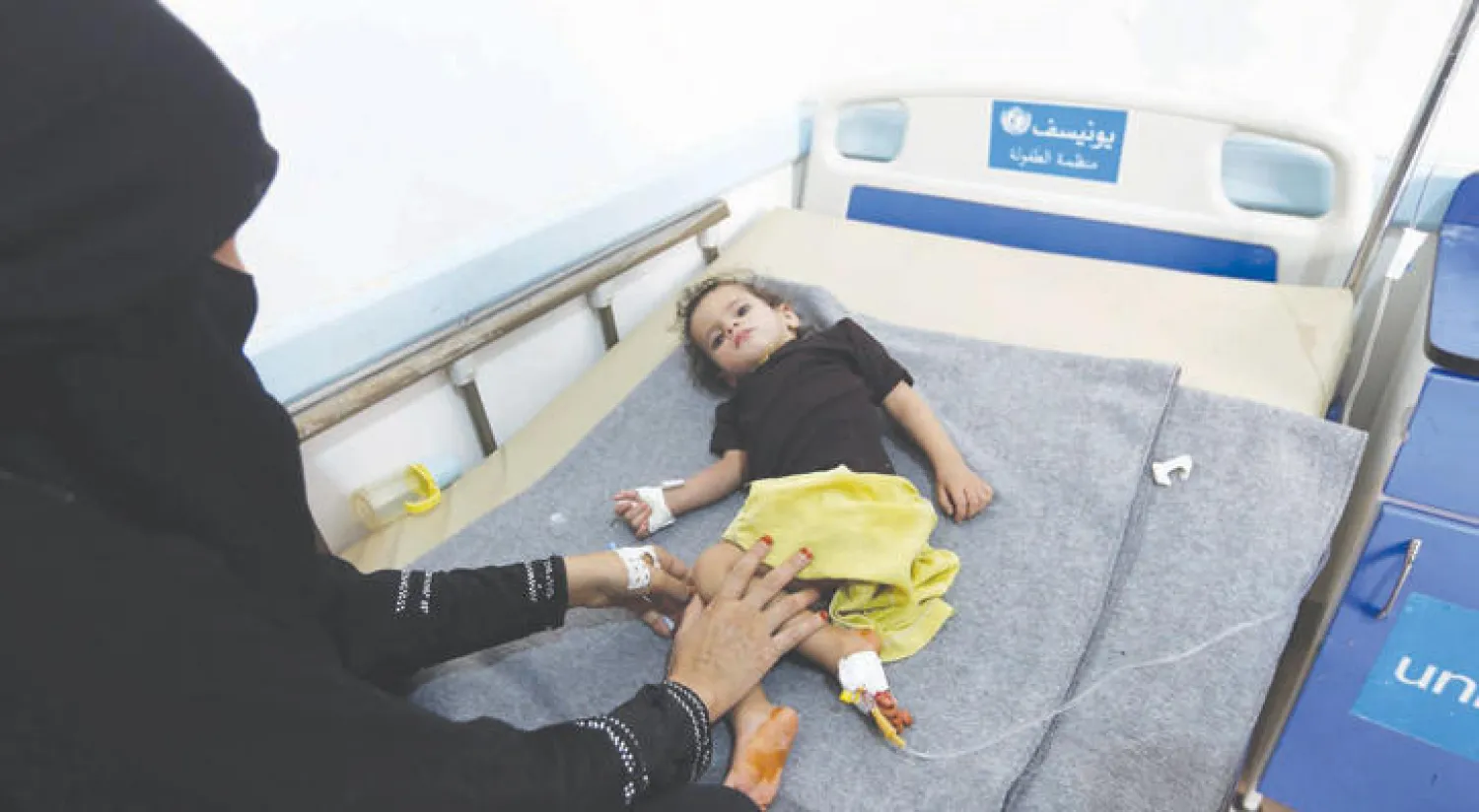 أم تجلس إلى جوار ابنتها التي تتلقى العلاج بأحد مستشفيات صنعاء