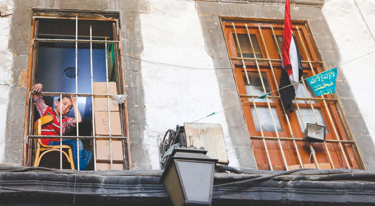 صبي يجلس أعلى محل في سوق الحميدية الشهير بالقسم القديم من دمشق (أ.ف.ب)