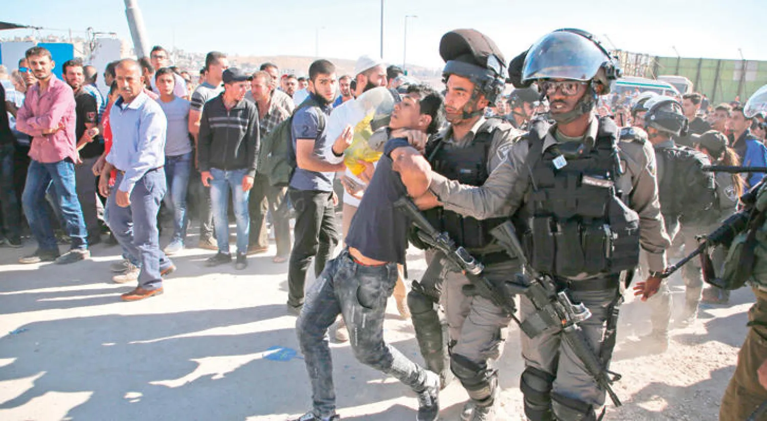 جنود إسرائيليون يعتقلون شاباً فلسطينياً في قلنديا بين القدس ورام الله أمس (أ.ف.ب)