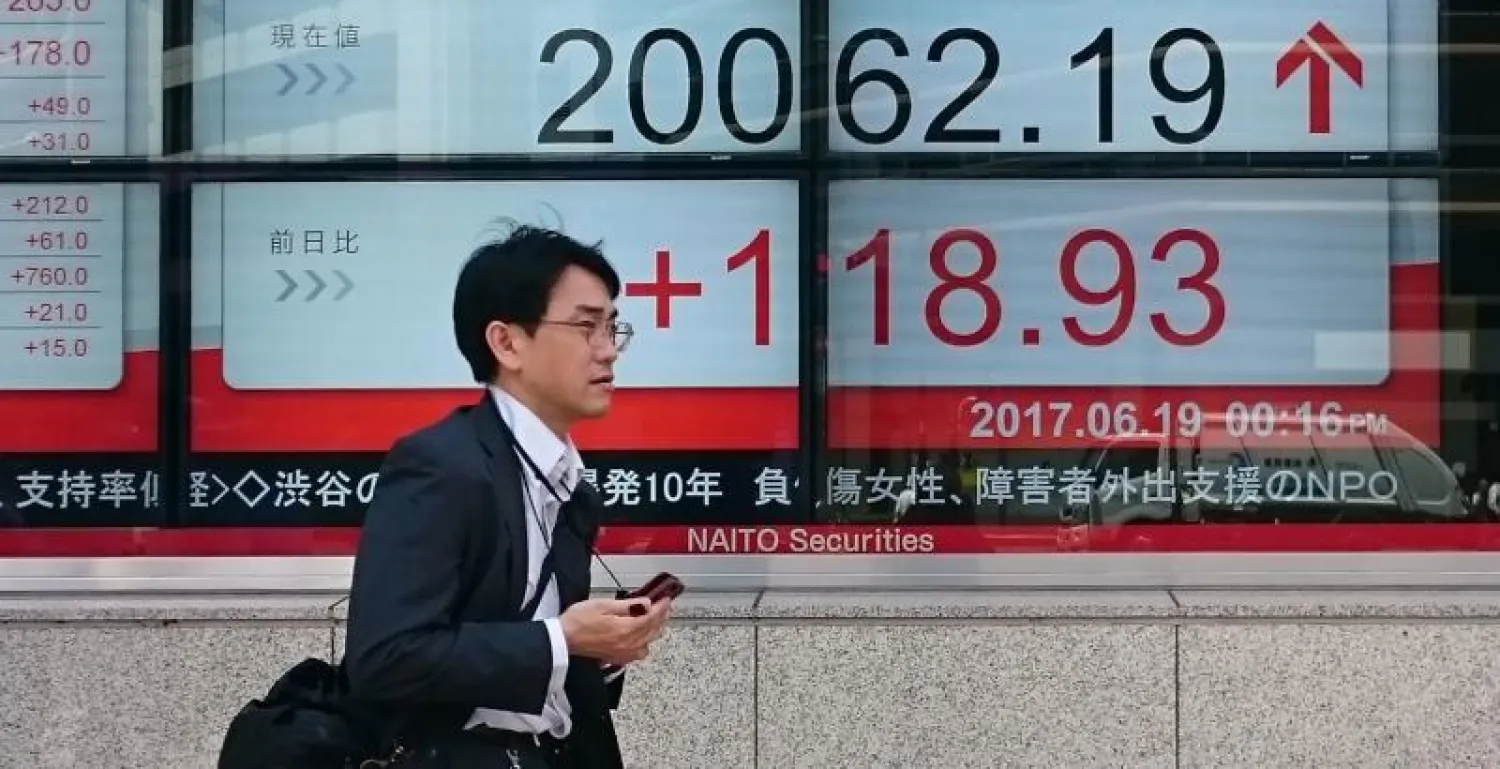 رجل يمر أمام لوحة تعرض مؤشر نيكي القياسي بطوكيو (أ.ف.ب)