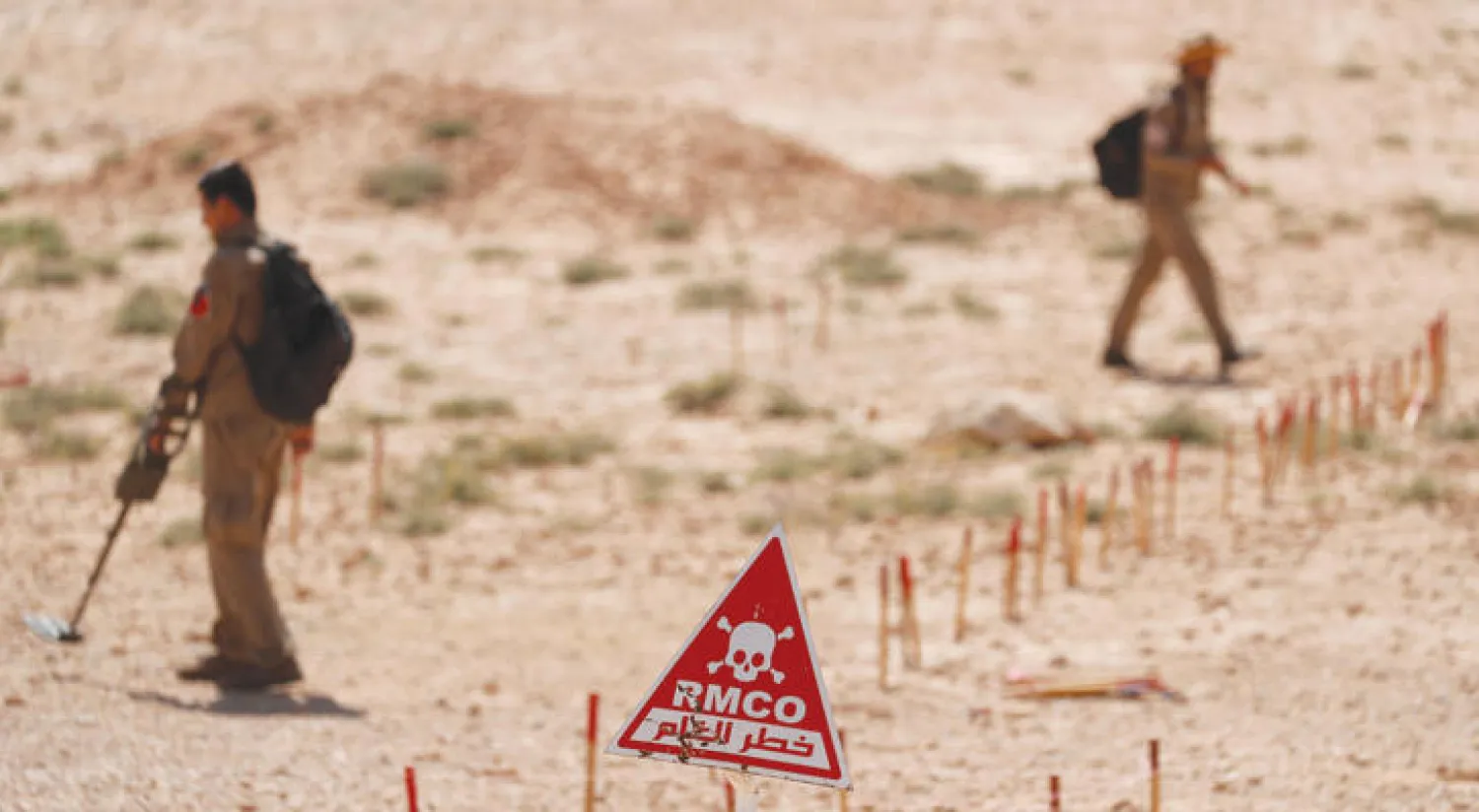 يبحثان عن ألغام زرعها «داعش» في قرية عين عيسى شمال الرقة (رويترز)