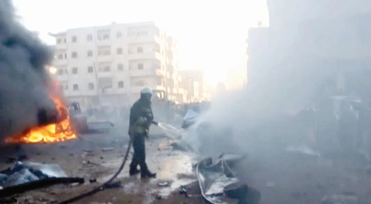 عناصر «الدفاع المدني» يطفئون النار بعد تفجير سيارة في ريف إدلب أمس (رويترز)