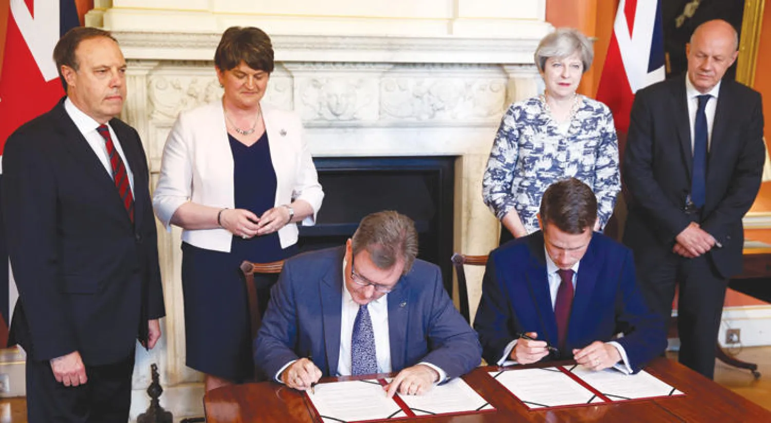 رئيسة الوزراء البريطانية (يمين) وزعيمة الحزب الوحدوي الديمقراطي بعد الإعلان عن التوصل إلى اتفاق لتشكيل الحكومة أمس (إ.ب.أ)