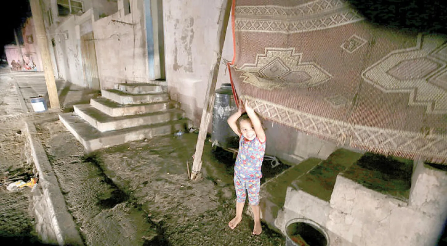 طفلة فلسطينية تلعب أمام منزل أسرتها في مخيم الشاطئ بقطاع غزة (إ.ب.أ)