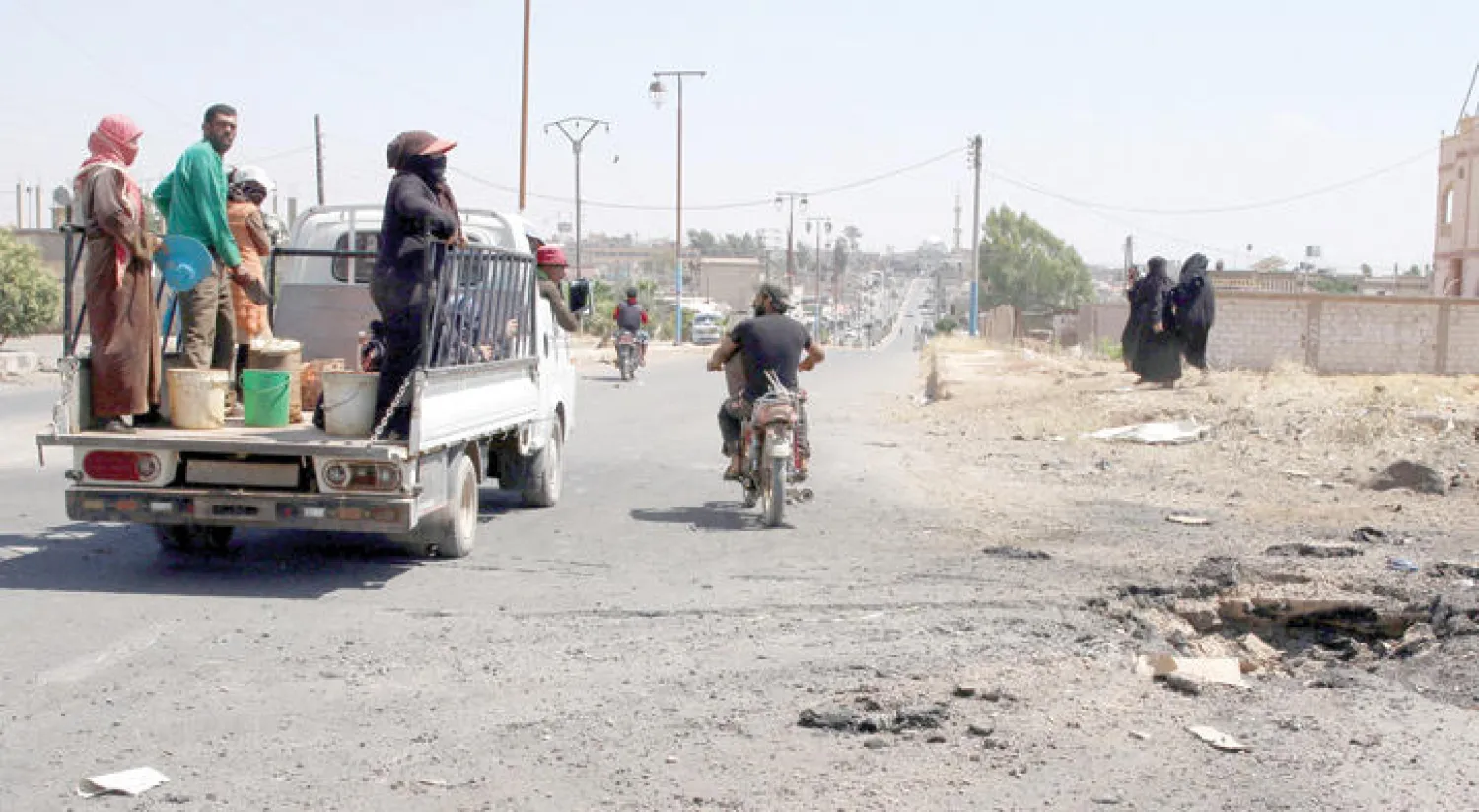 سوريون يمرون قرب مكان تعرض لغارة في ريف درعا (رويترز)