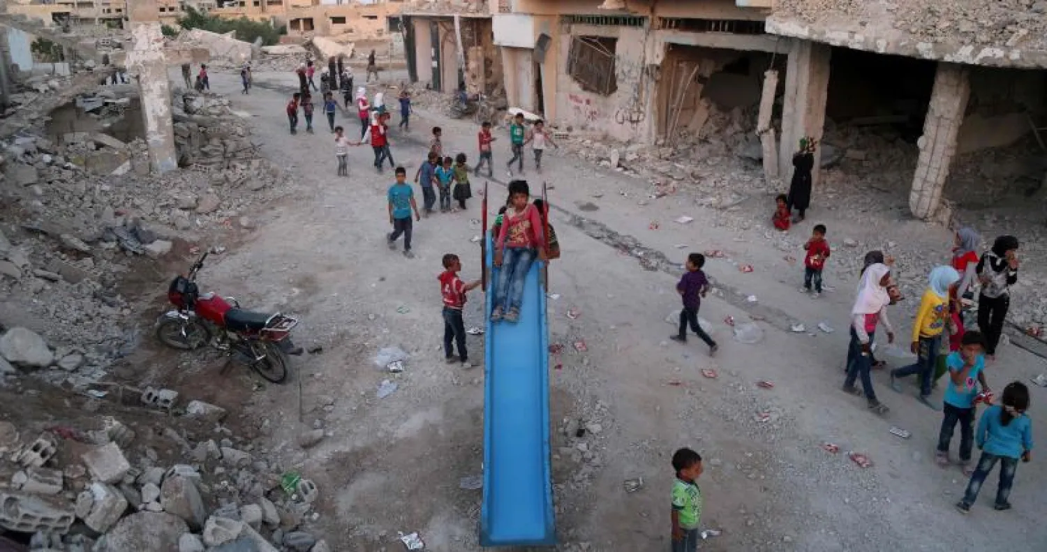 أطفال سوريون فروا من ديارهم في بلدة الغوطة يلعبون وسط أنقاض المباني في بلدة النشبية بمنطقة الغوطة الشرقية معقل المعارضة (أ.ف.ب)