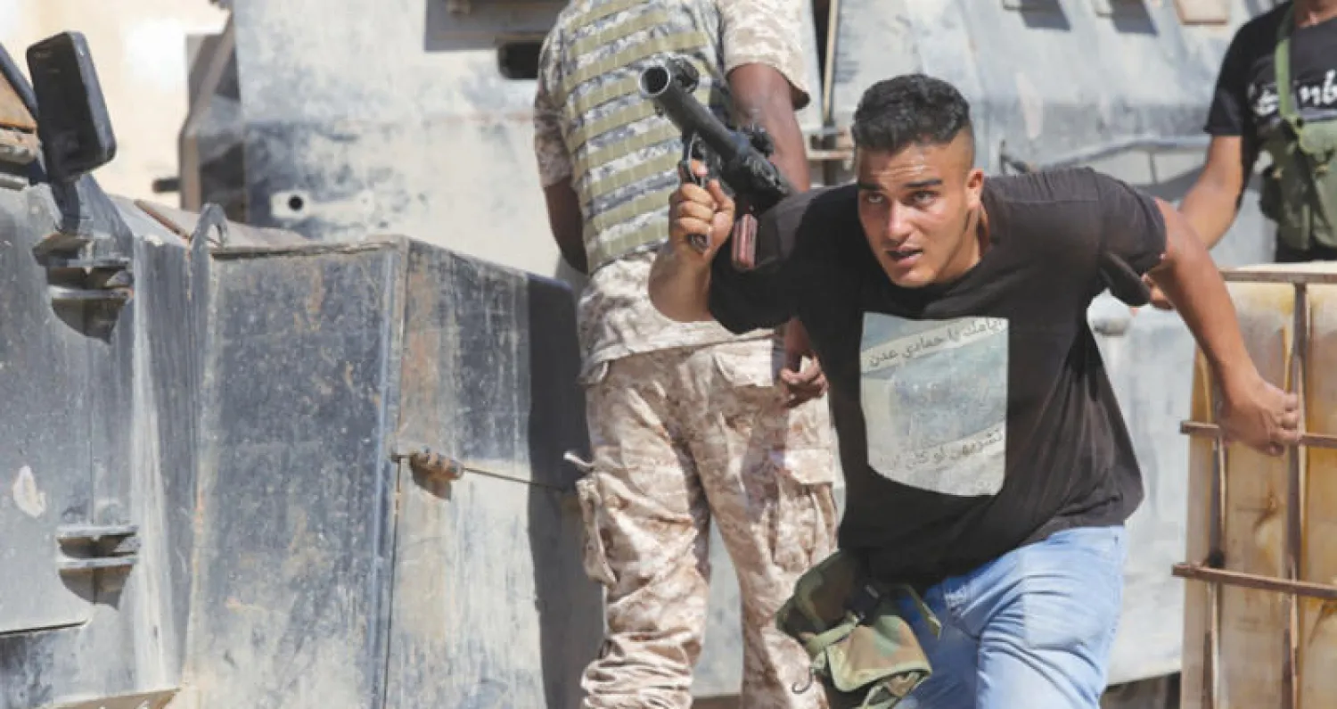 ليبي يفر من القتال في شوارع بنغازي قبل تحريرها بالكامل (رويترز)