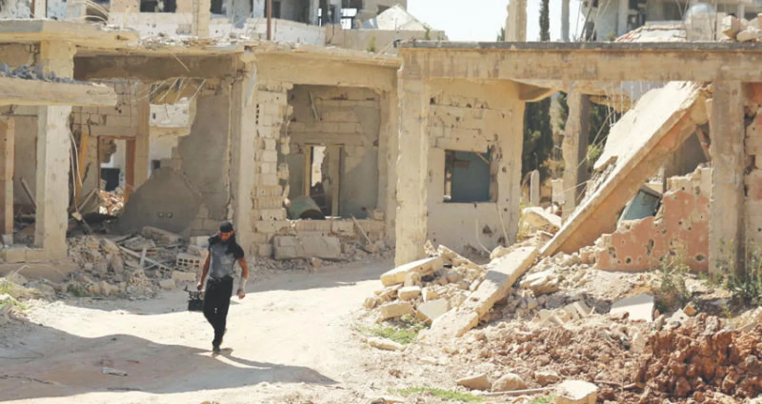 مقاتل من الجيش السوري الحر يعبر أبنية مدمرة بمنطقة تسيطر عليها المعارضة في درعا جنوب سوريا (رويترز)