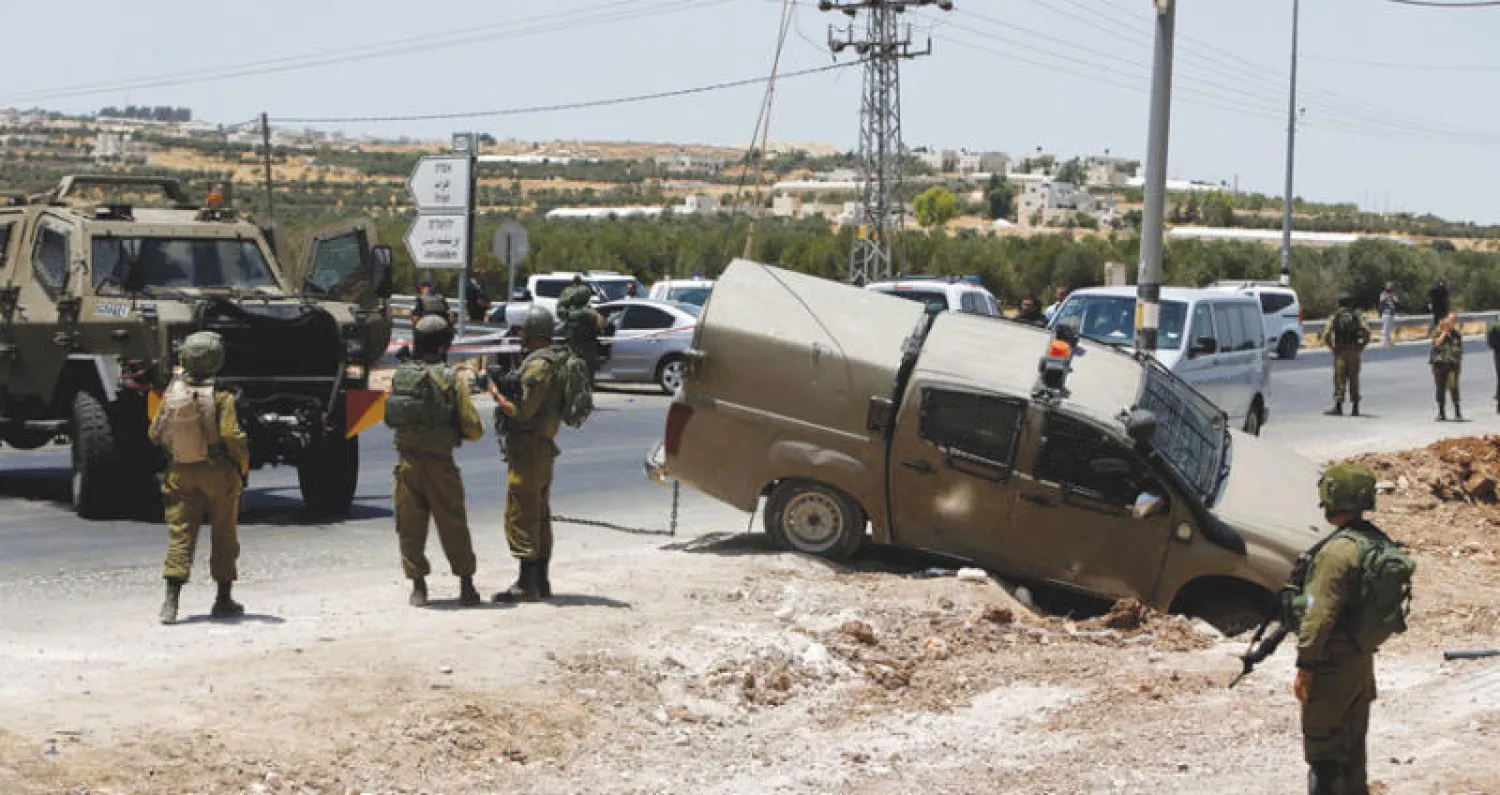 جندي إسرائيلي يحرس السيارة التي تقول سلطات الاحتلال إن الفلسطيني القتيل استخدمها في عملية دهس (رويترز)